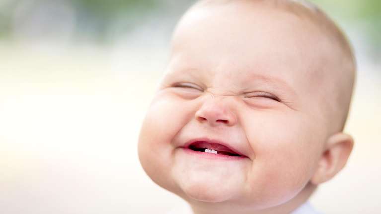 A baby giggling in Northborough showing his first two teeth
