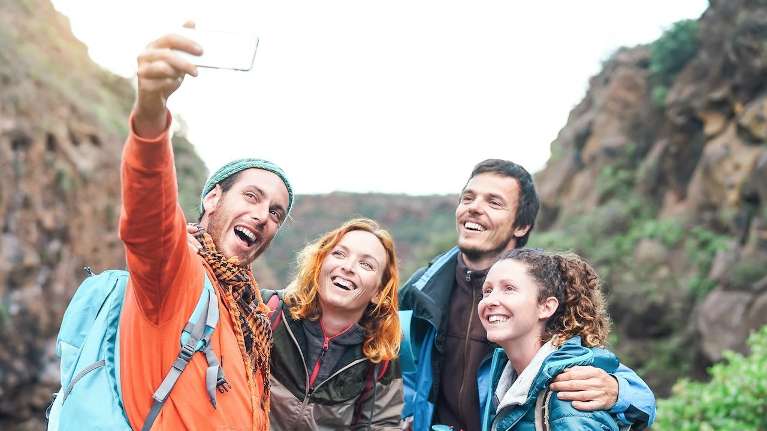 all smiling and holding up a smartphone to take a selfie