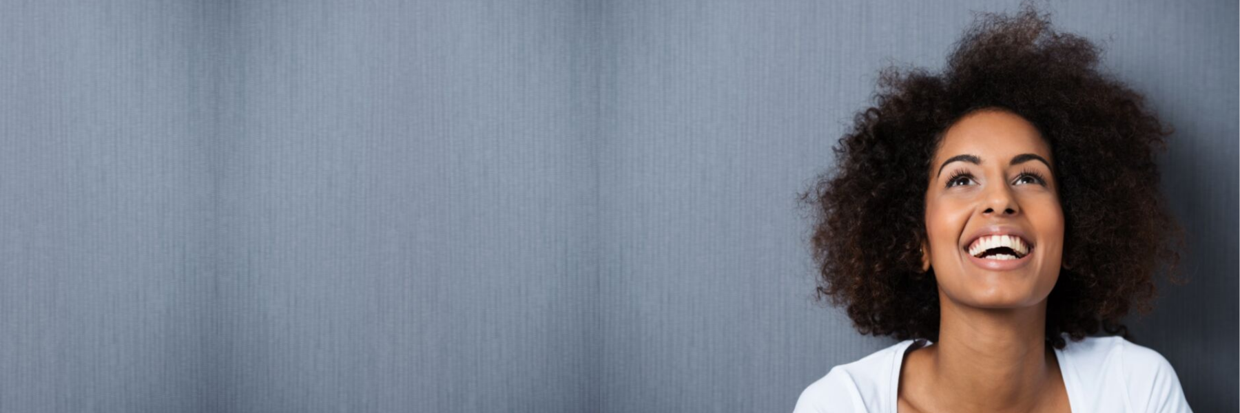 Woman smiling against a gray wall at dentist in Northborough MA
