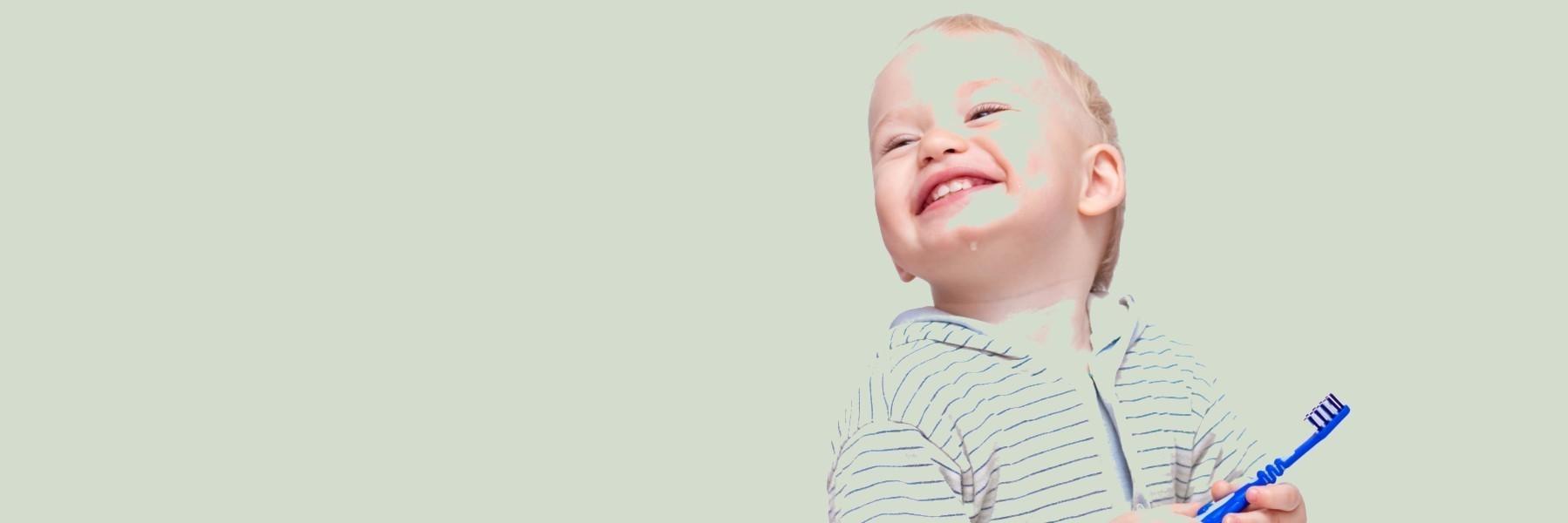 Infant holding tooth brush at dentist in Northborough